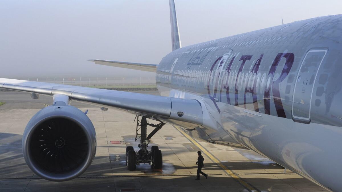 A person walks under a Qatar Airways Airbus A350-900 at the Airbus Group center in Toulouse, France, in December 2014. Qatar Airways is responding to a blockade by its Middle Eastern neighbors by adding 16 destinations.