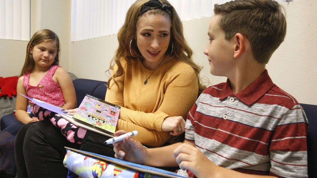 Group facilitator Rebeccah Glisson, 25, talks with siblings Emily Roberts, 7, left, and Nathan Roberts, 10, before a children's grief support group at The Elizabeth Hospice Children's Bereavement Center in Escondido last week. The children's father died two years ago.