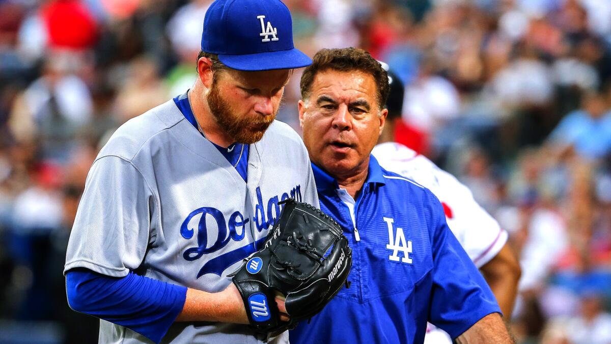 Dodgers starting pitcher Brett Anderson exits the game with trainer Stan Conte after injuring his left Achilles' tendon during the game against the Braves onJuly 21 in Atlanta.