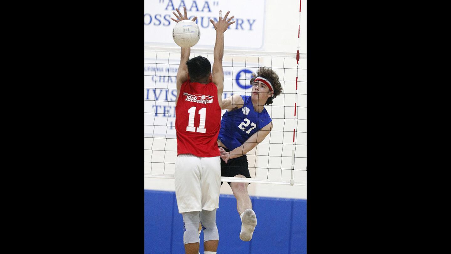 Burbank's Ryan Rickey hits a kill through the arms of Burroughs' Jose Solano to win the second game in a rival Pacific League boys' volleyball game at Burban High School on Thursday, April 26, 2018.