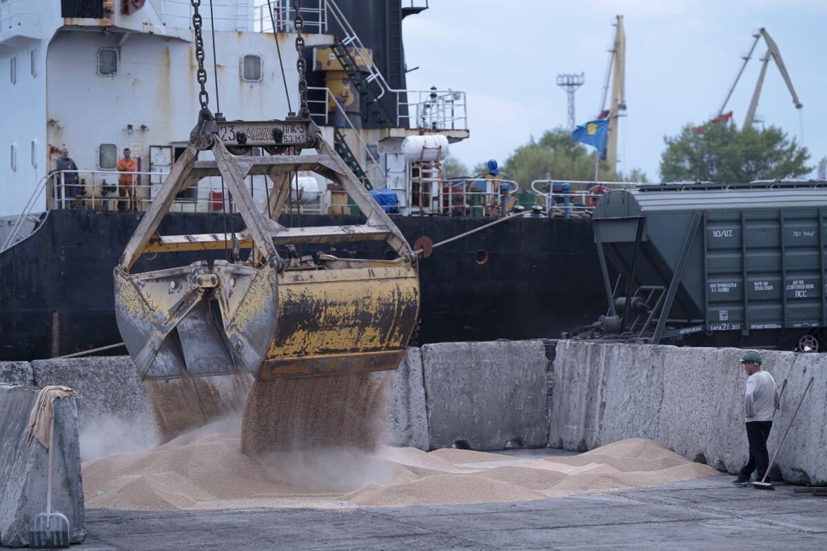 Workers use a large machine to load grain at a port