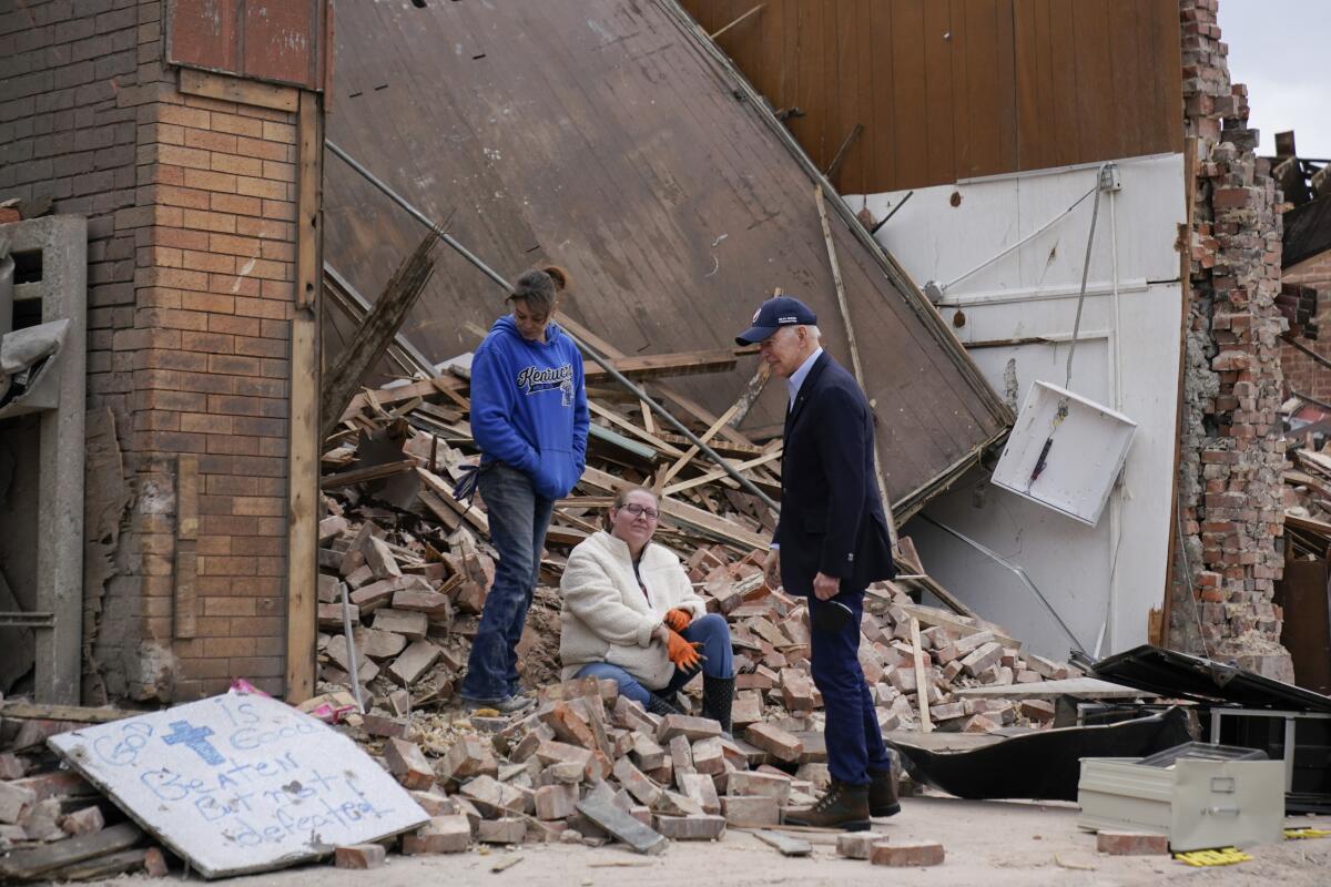 President Biden looks over damage from tornadoes and talks to two people