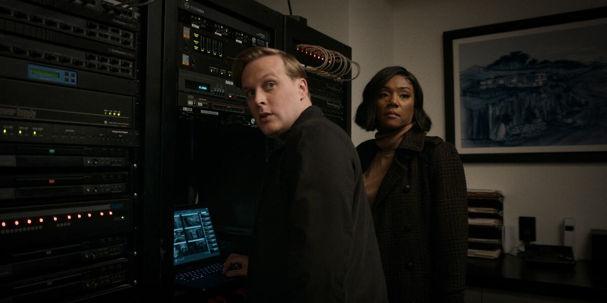 Two detectives standing before a wall of technology