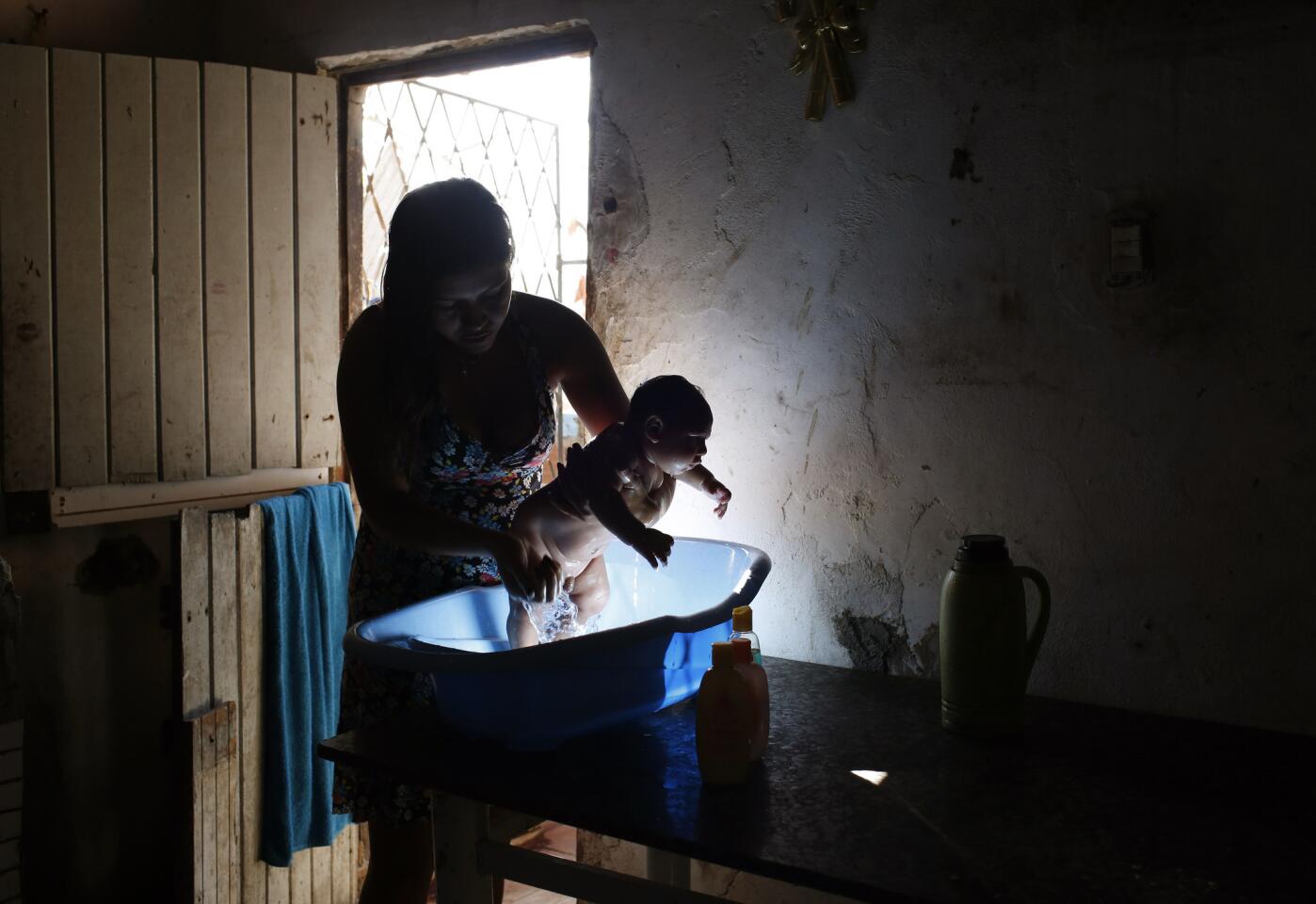 Ana Carolina da Silva Amorim bathes her cousin, Samuel, who was born with microcephaly. The neighborhood where they live in Campina Grande is infested with mosquitoes.