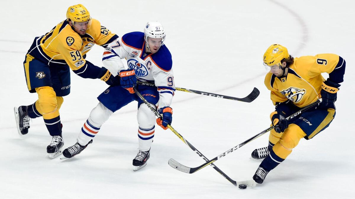 Edmonton's Connor McDavid maneuvers the puck between Nashville's Roman Josi, left, and Filip Forsberg on Feb. 26.