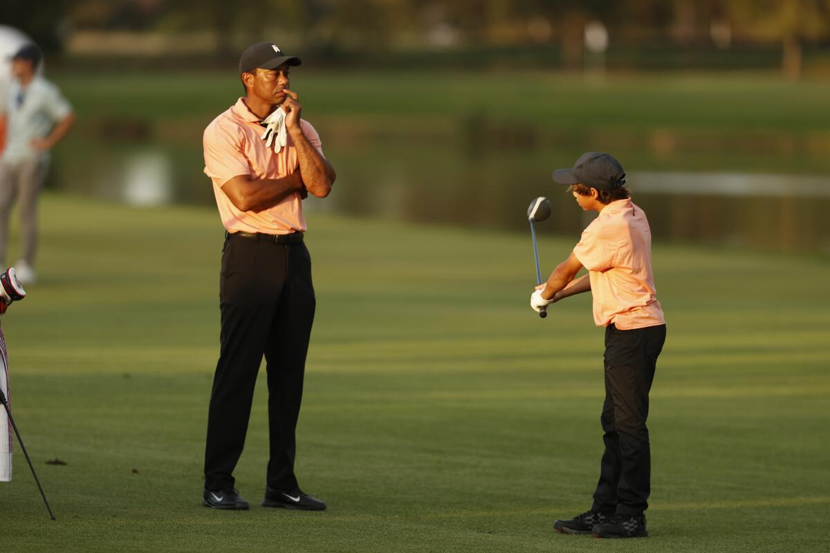Tiger Woods stands with his son Charlie, 12, on the 18th fairway during the first round of the PNC Championship.