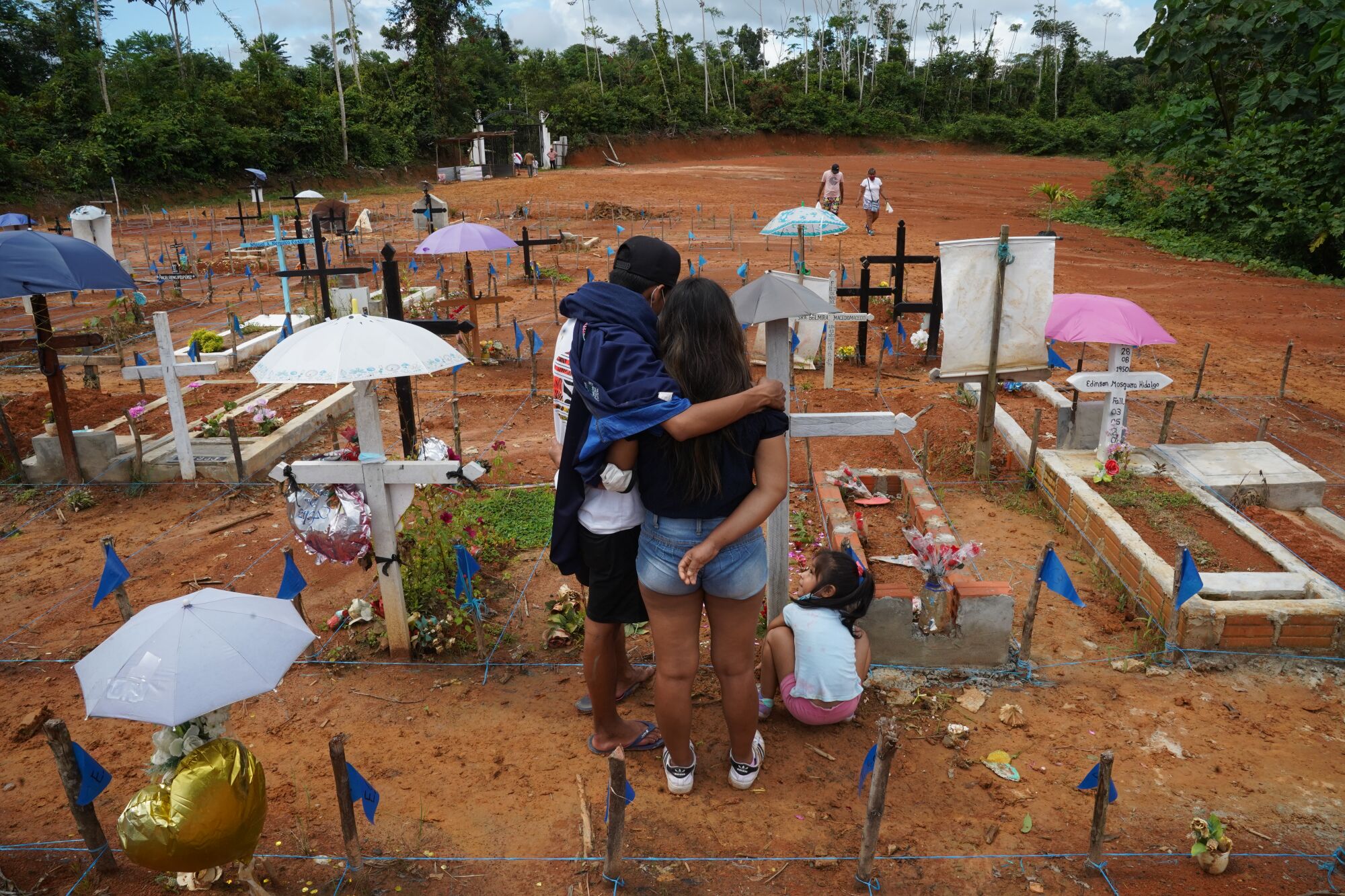 Marylin Tenant 25, and her daughter Dana, 5, and a companion, visit the cemetery outside Iquitos where her father is buried.