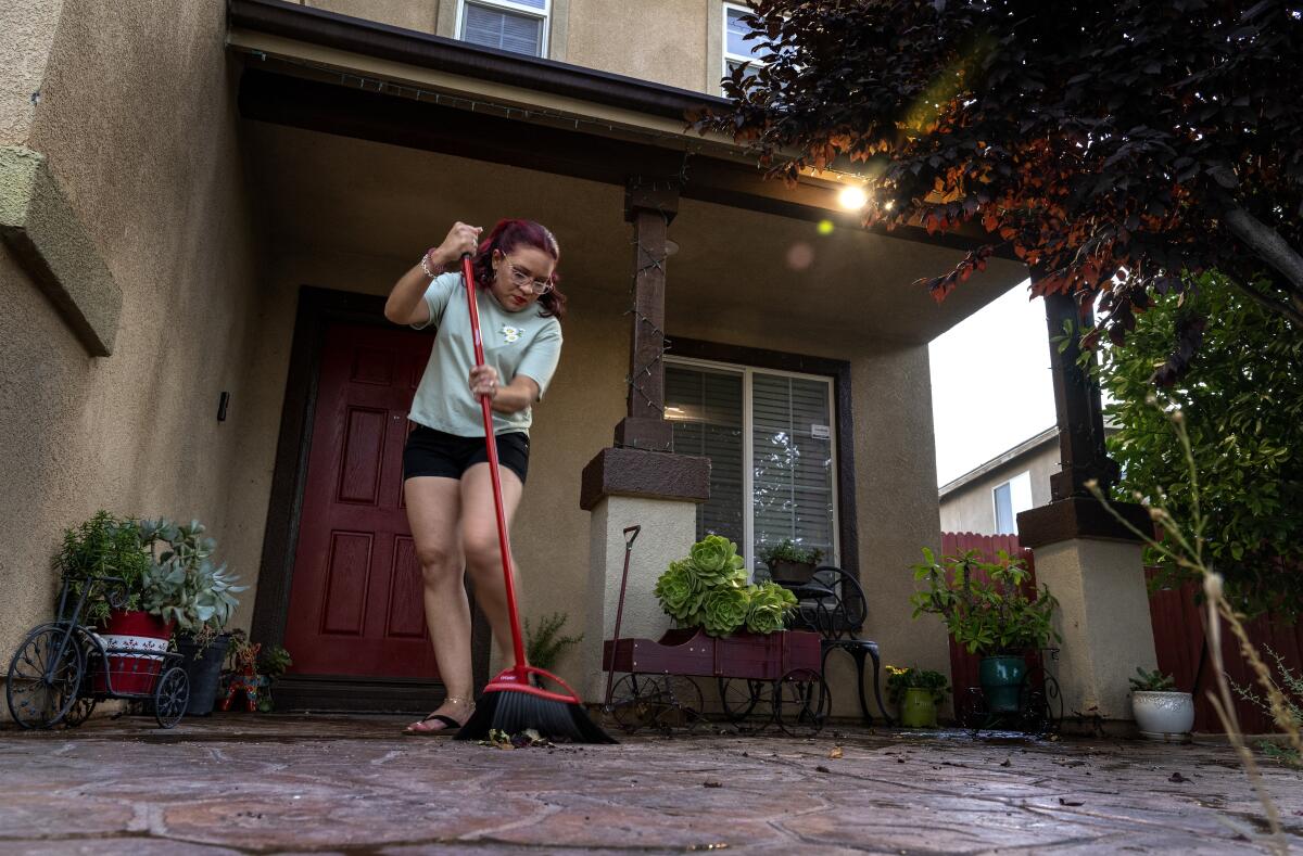 Gladis Avila sweeps her front porch.