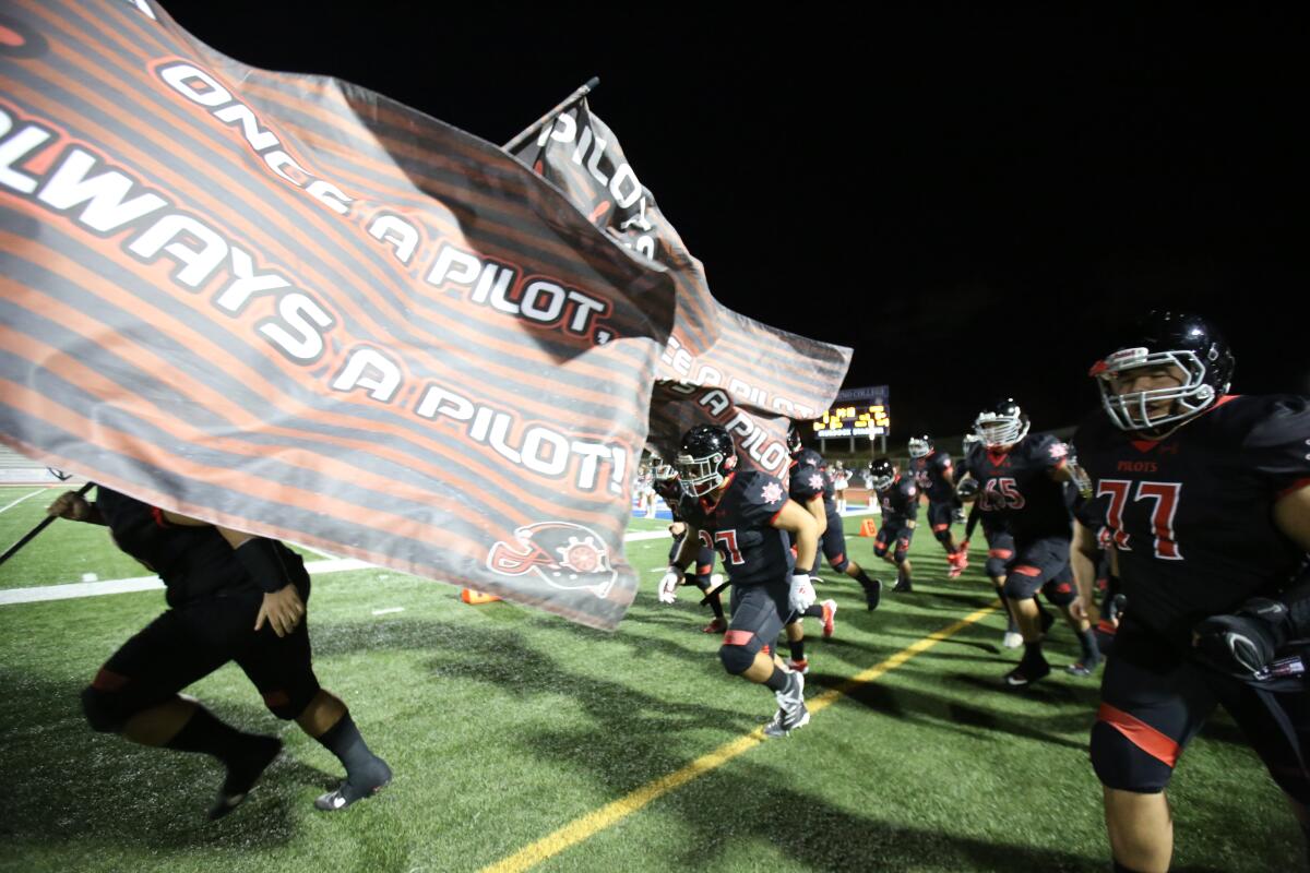 Banning football players break through a banner as they run on to the field.