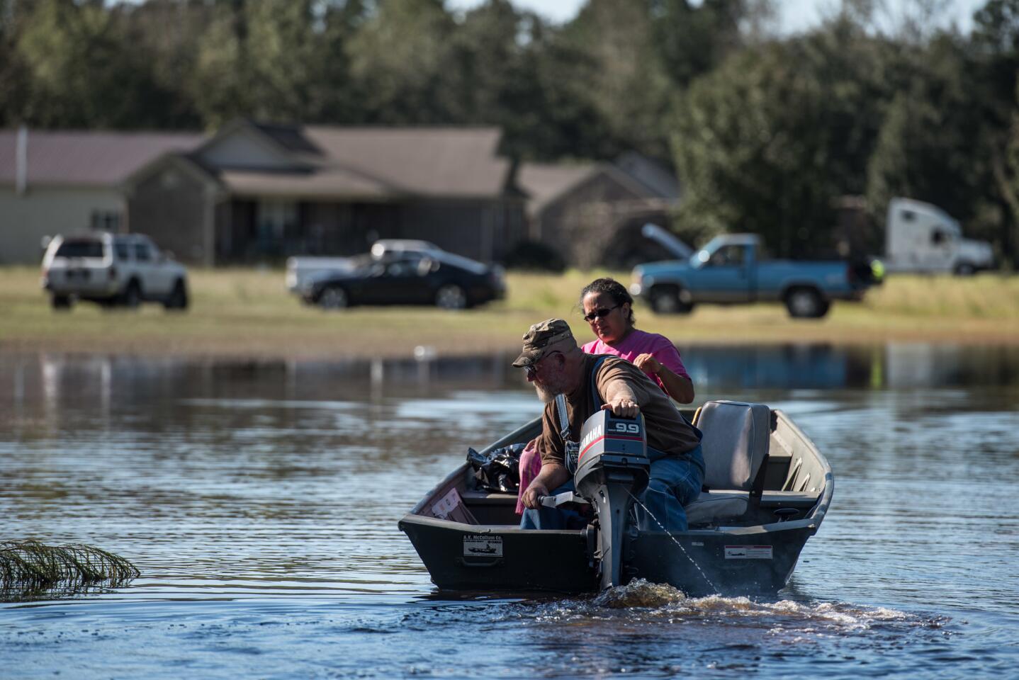 A man and woman land a boat on a front yard on Oct. 10, 2016, in Lumberton, North Carolina.