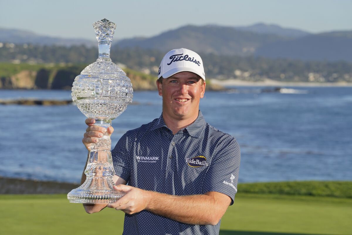 Tom Hoge poses with his trophy on the 18th green of the Pebble Beach Golf Links after winning the AT&T Pebble Beach Pro-Am golf tournament in Pebble Beach, Calif., Sunday, Feb. 6, 2022. (AP Photo/Eric Risberg)