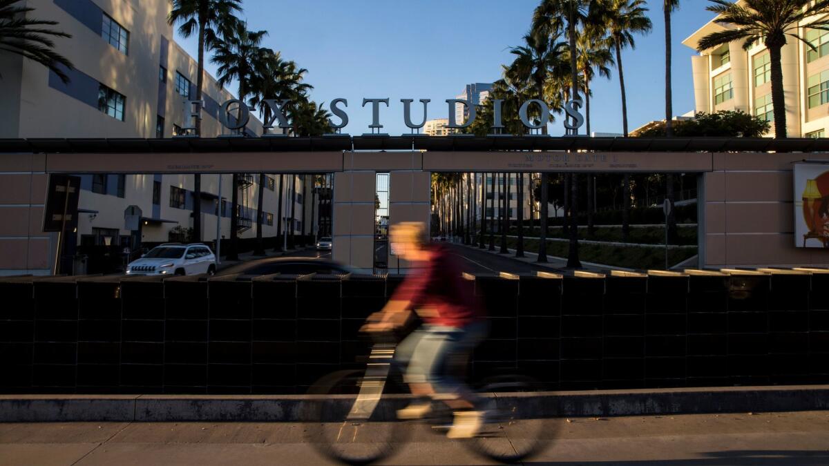 A bicyclist rides by 20th Century Fox Studios on West Pico Boulevard in Century City.