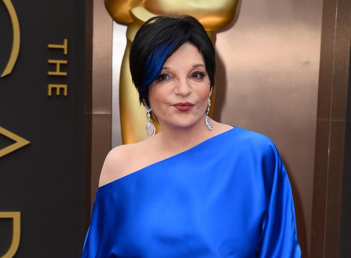 Liza Minnelli is seen in a blue off-the-shoulder gown with matching blue streak in her hair on the red carpet.