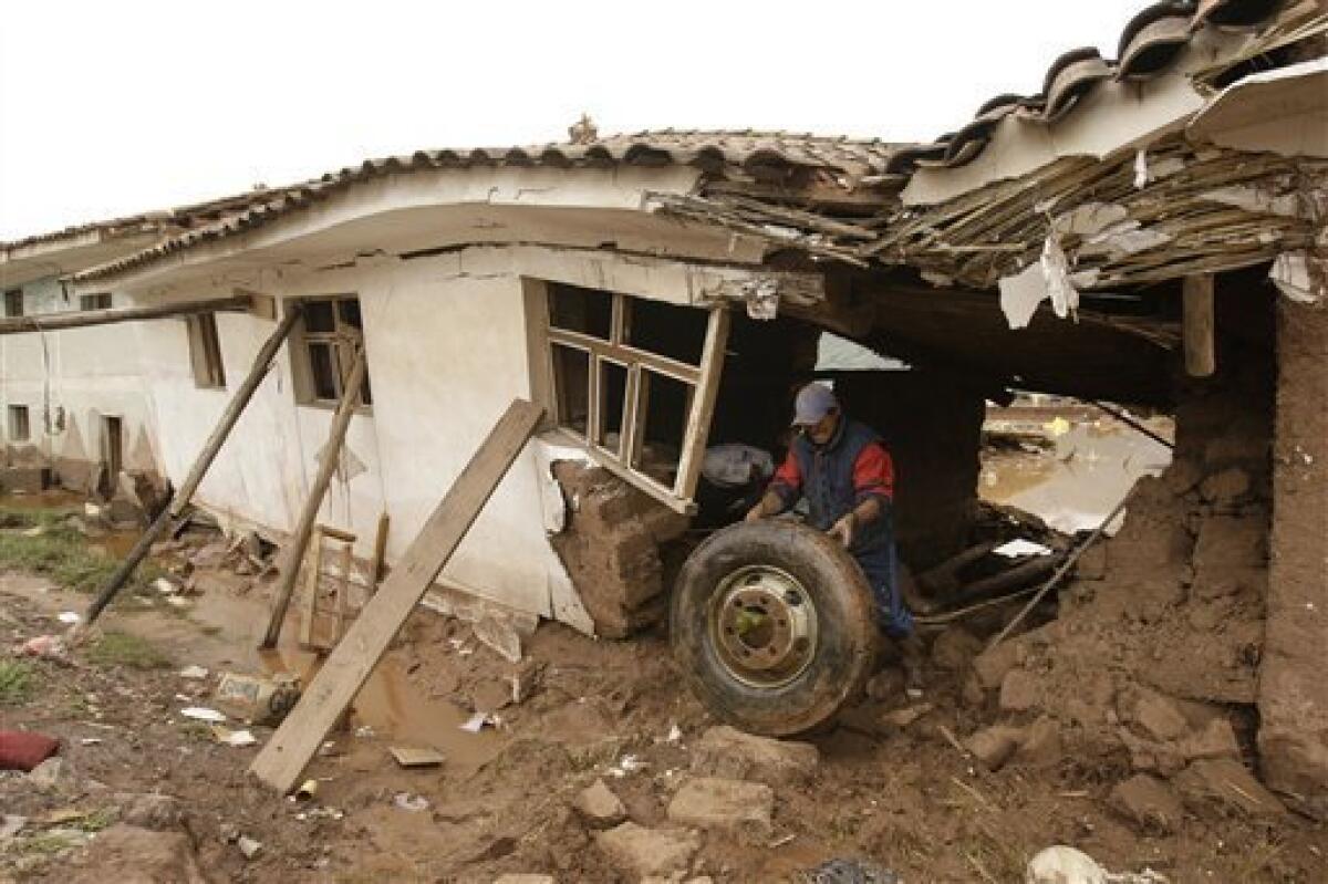 A man removes a tire from his house that was damaged when the Huatanay river overflowed in Cuzco, Peru, Wednesday, Jan. 27, 2010. Heavy rains and mudslides in Peru have blocked the train route to the ancient Inca citadel of Macchu Picchu, leaving nearly 2,000 tourists stranded.(AP Photo/Martin Mejia)
