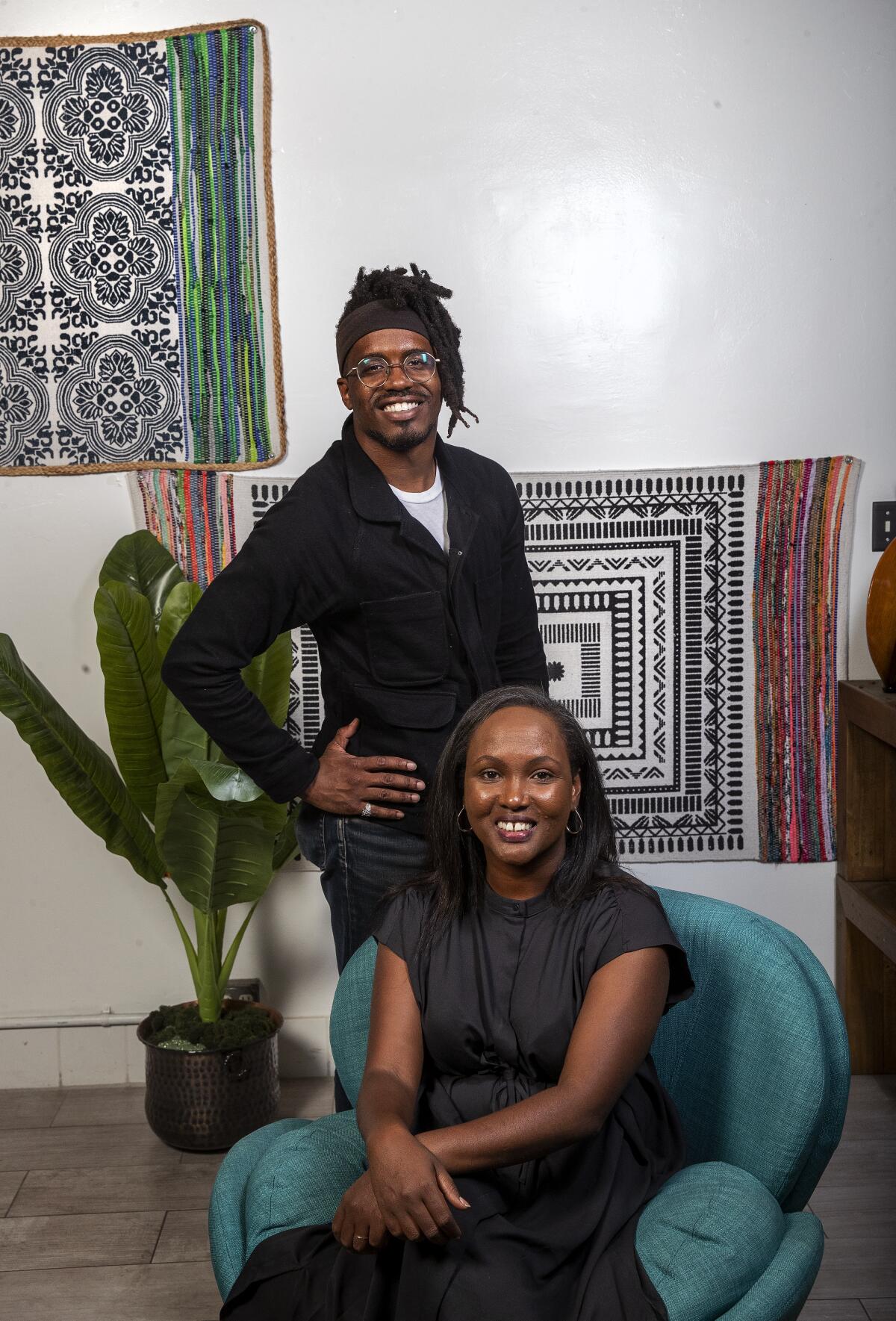 Meymuna Hussein-Cattan and Christian Davis are photographed against a white wall.