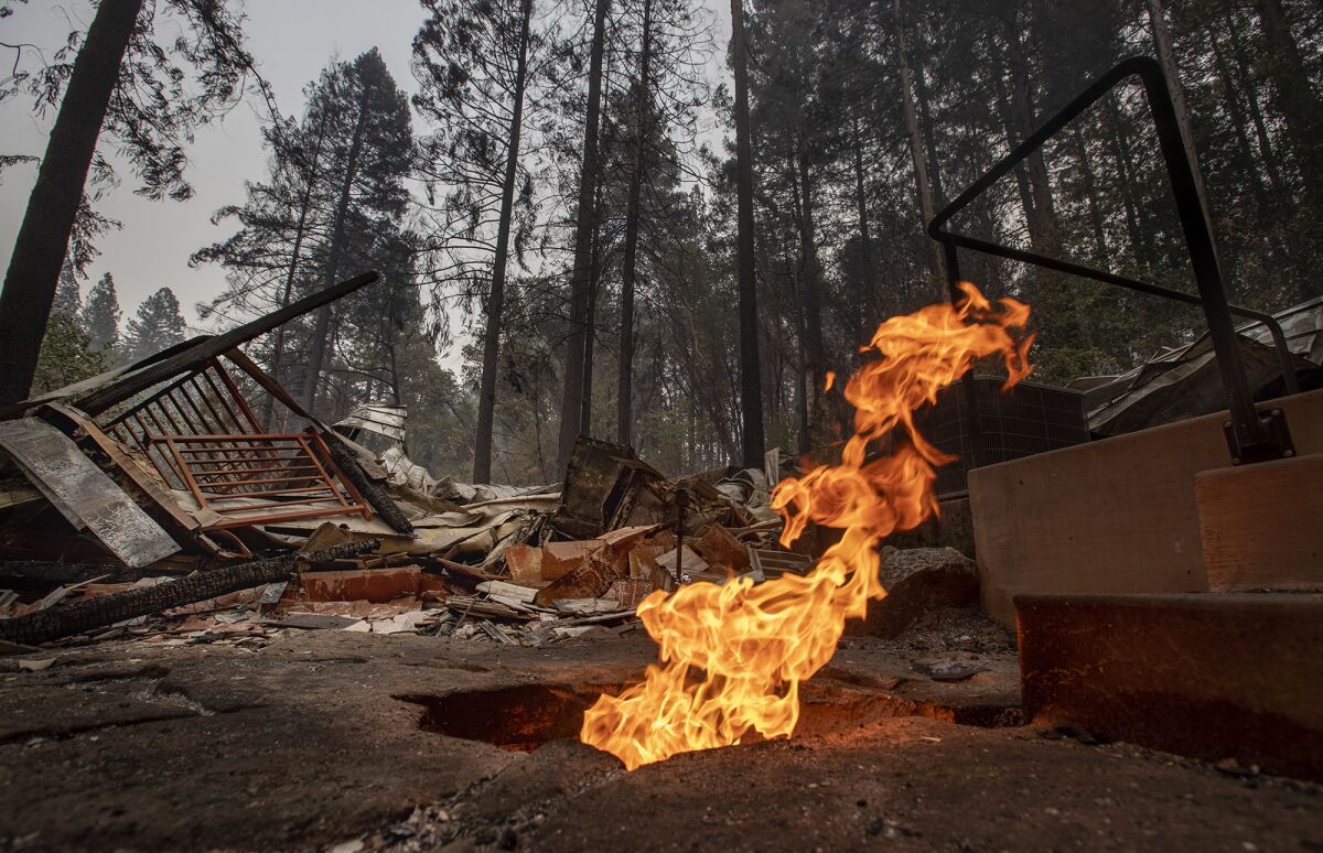 Flames shoot out of a broken gas line at a home destroyed in Berry Creek, Calif.