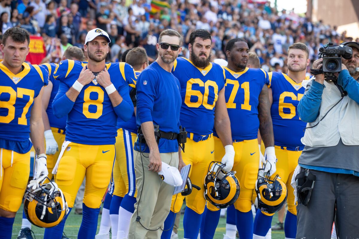 Rams offensive lineman Chandler Brewer (67, right) stands with teammates on the sideline.
