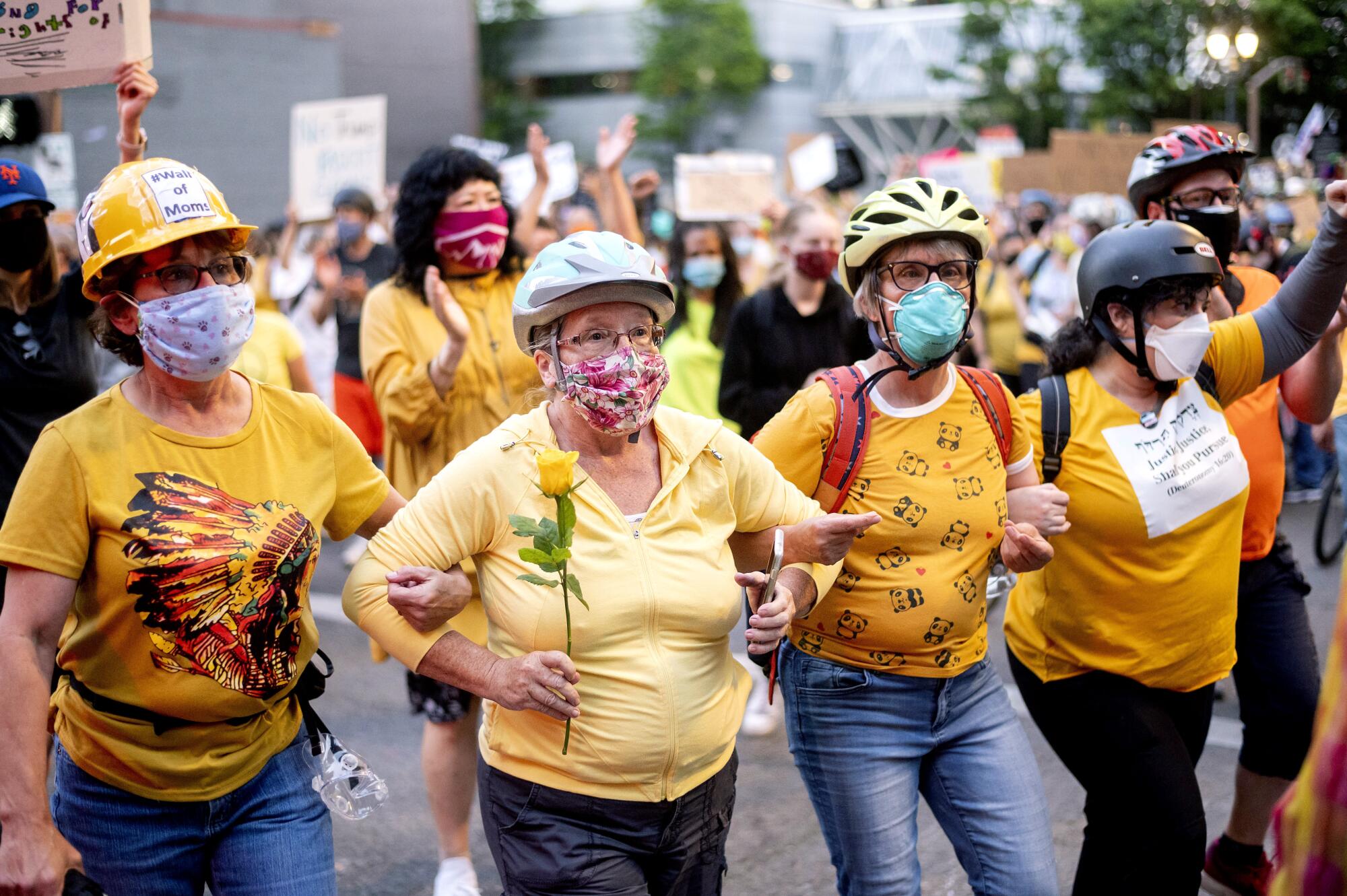 Norma Lewis holds a flower while forming a "Wall of Moms" during a Black Lives Matter protest in Portland, Ore.