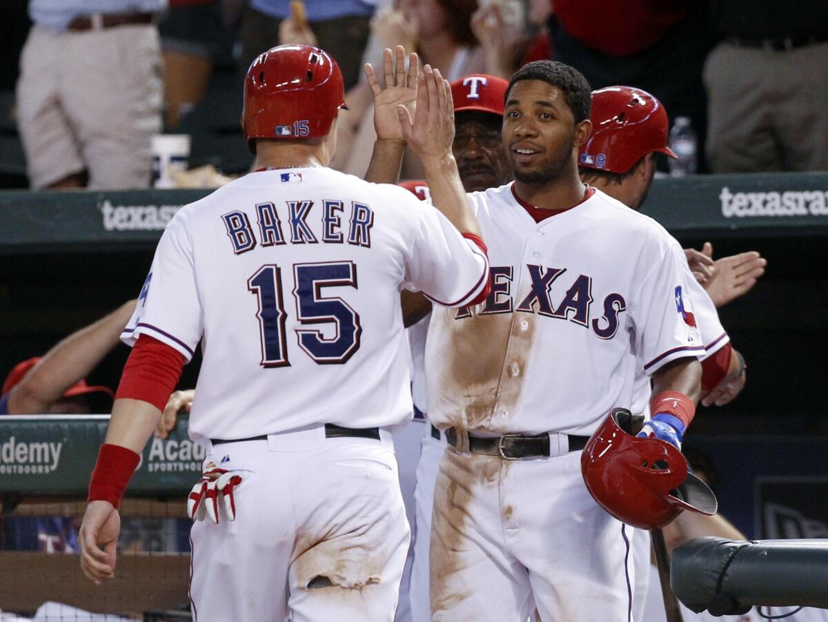 Jeff Baker, left, is congratulated by Texas Rangers teammate Elvis Andrus after scoring a run during the Angels' 14-11 loss on Tuesday.