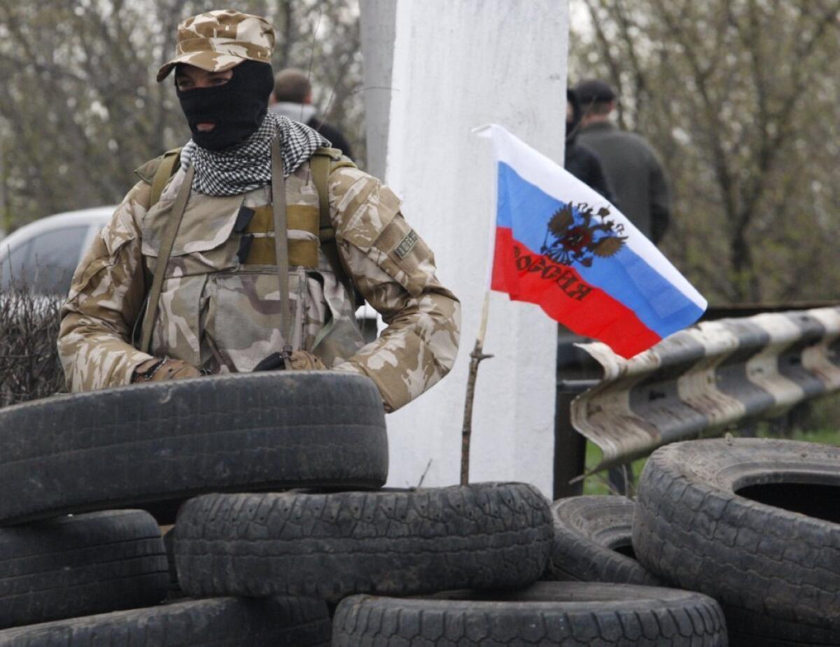 An armed pro-Russia activist guards a checkpoint on the Kharkiv-Donetsk road near the entrance to the eastern Ukrainian city of Slavyansk.