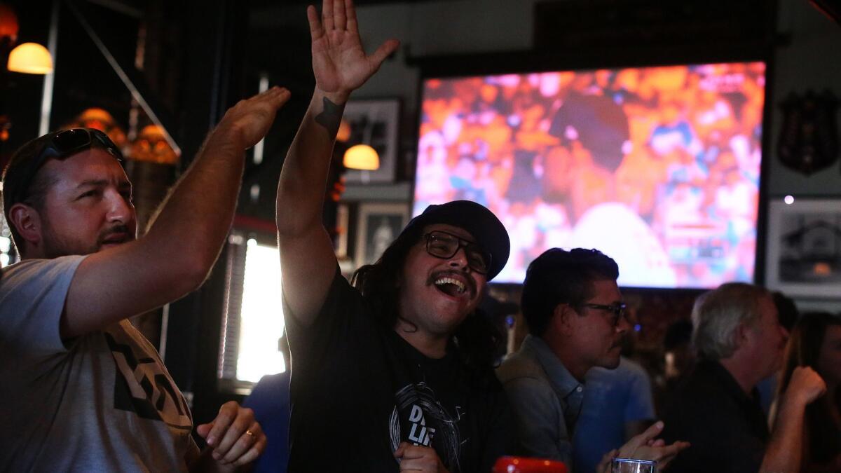 George Montejano and Jorge Pallares cheer on the Dodgers at the Greyhound Bar & Grill.