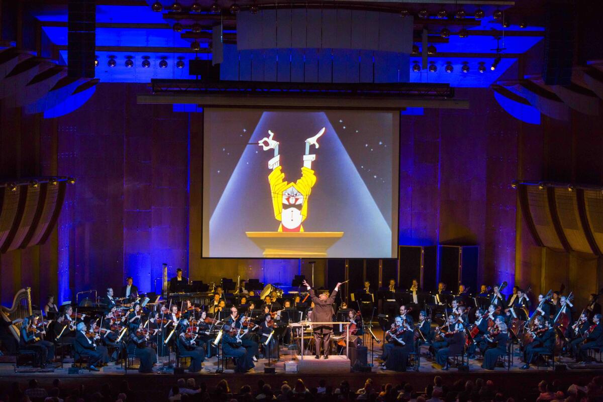 The image of a cartoon rabbit is projected on a movie screen above an orchestra