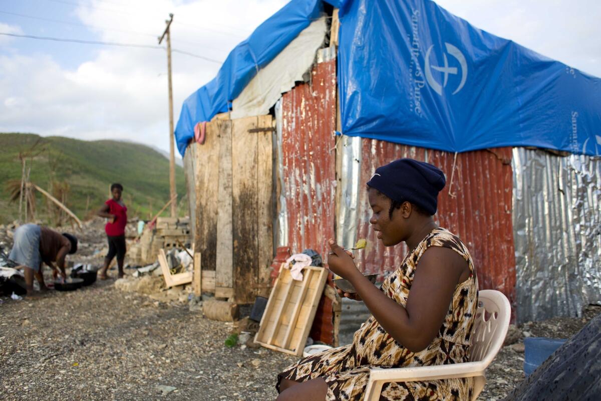 En esta imagen del 31 de octubre de 2016, Nathanaelle Bernard, embarazada de 7 meses, come un bol de maíz con pasta de judías, sentada ante una choza improvisada que comparte con cinco familiares en Coteaux, Haití. (AP Foto/Dieu Nalio Chery)