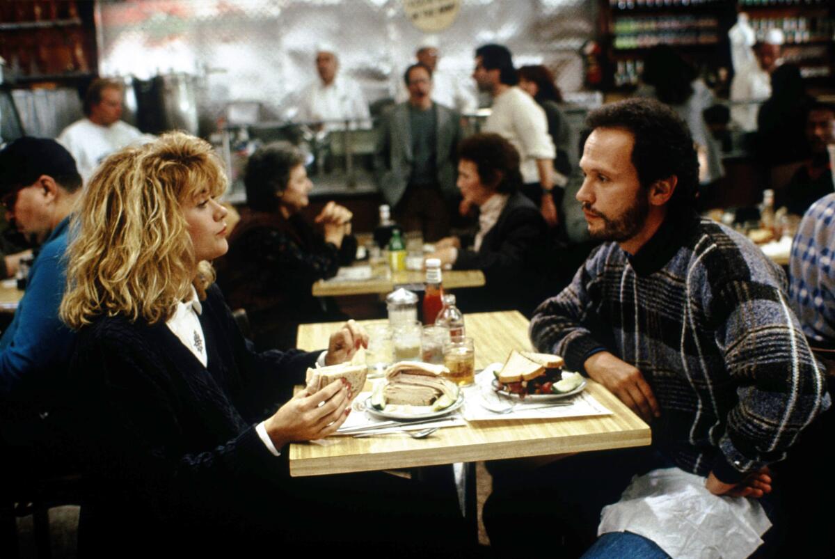 A woman and a man face each other across a table in a busy restaurant.