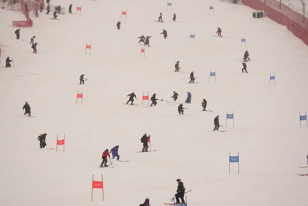 Workers clear snow from the course after the second run of the men's giant slalom was delayed due to a heavy snowfall at the 2022 Winter Olympics, Sunday, Feb. 13, 2022, in the Yanqing district of Beijing. (AP Photo/Robert F. Bukaty)