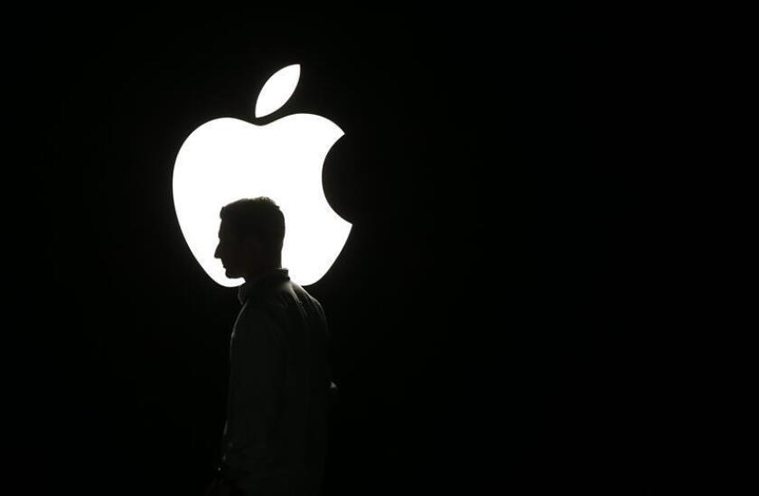 La silueta de un hombre se ve frente al logo de Apple. EFE/Archivo