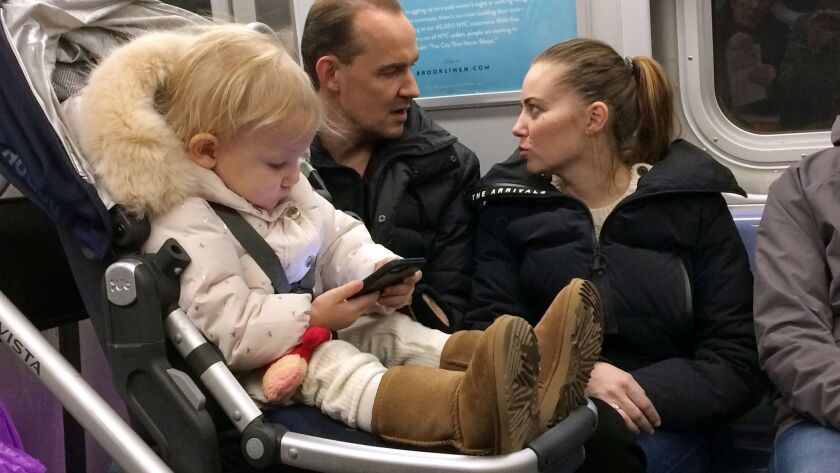A small child plays with a cellphone while riding in a New York subway in December.