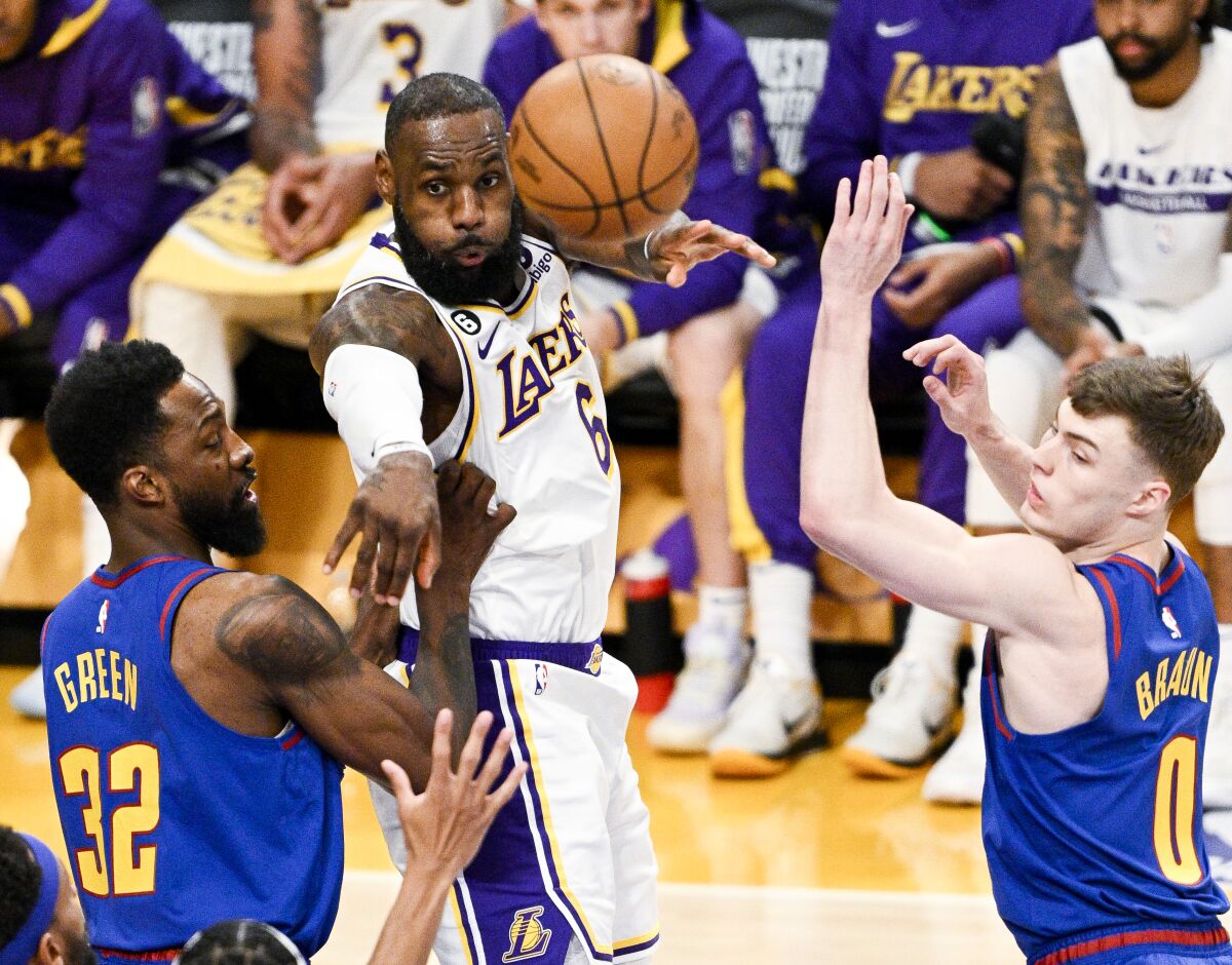 Lakers forward LeBron James, center, passes the ball while defended by Denver's Jeff Green, left, and Christian Braun.
