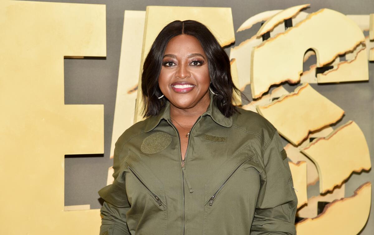 A woman with black hair smiles as she poses in front of a backdrop.