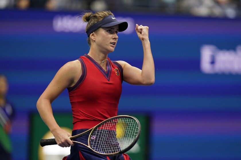 Elina Svitolina, holding a racket, punches the air.