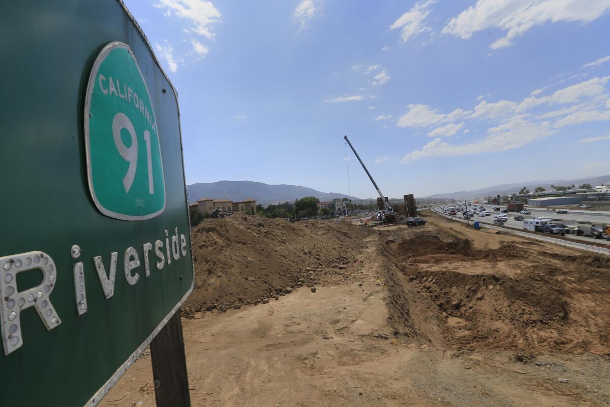 A 91 Freeway sign near a construction site filled with dirt