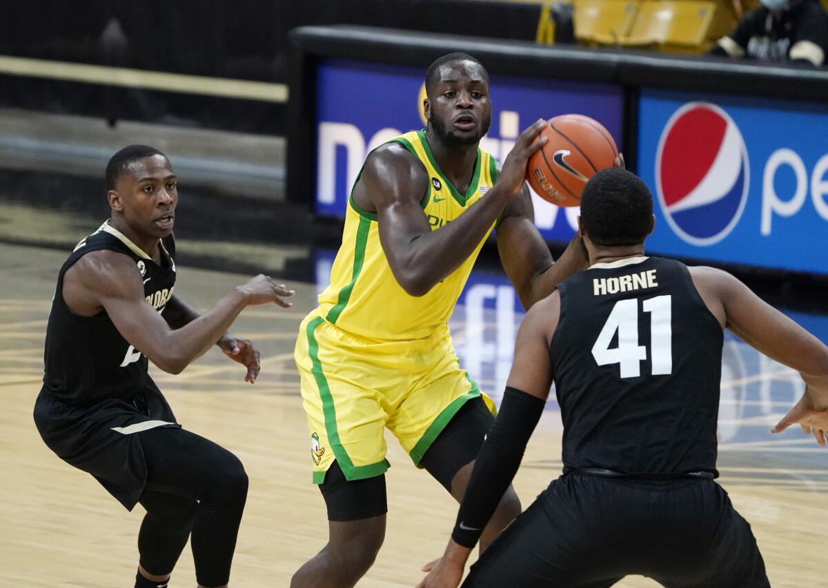 Oregon forward Eugene Omoruyi drives between Colorado guard McKinley Wright IV and forward Jeriah Horne.