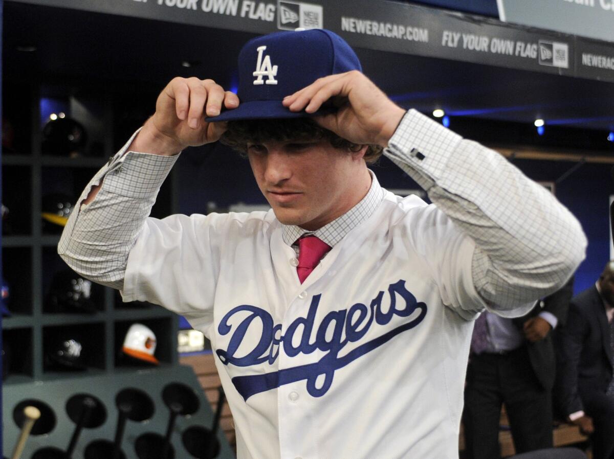Pitcher Grant Holmes from Conway High School in South Carolina puts on a Dodgers hat after being selected by L.A. in the first round of the MLB first-year player draft.