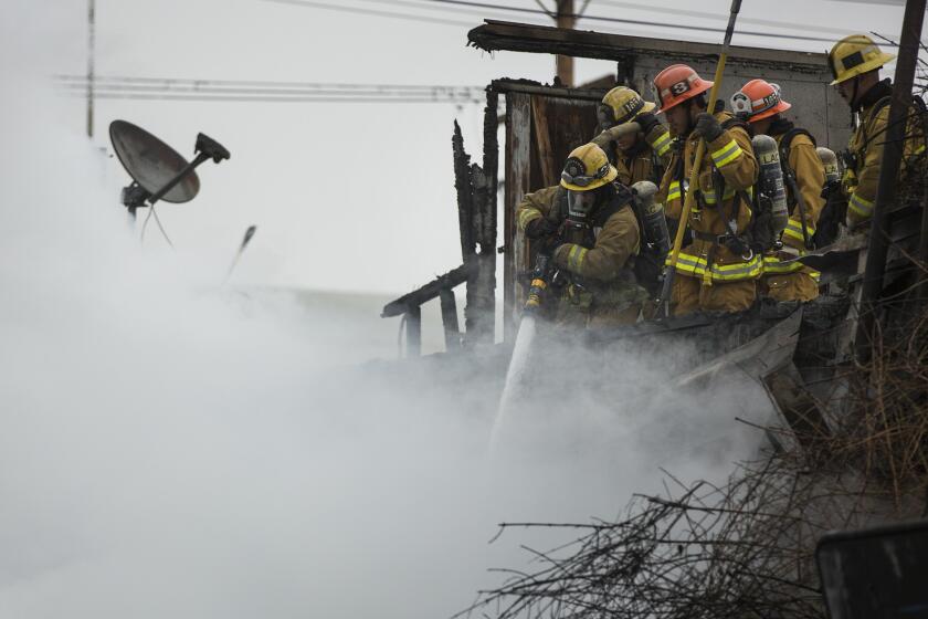 Firefighters spray water from the roof of a Maywood warehouse where an explosive fire burned earlier this month.