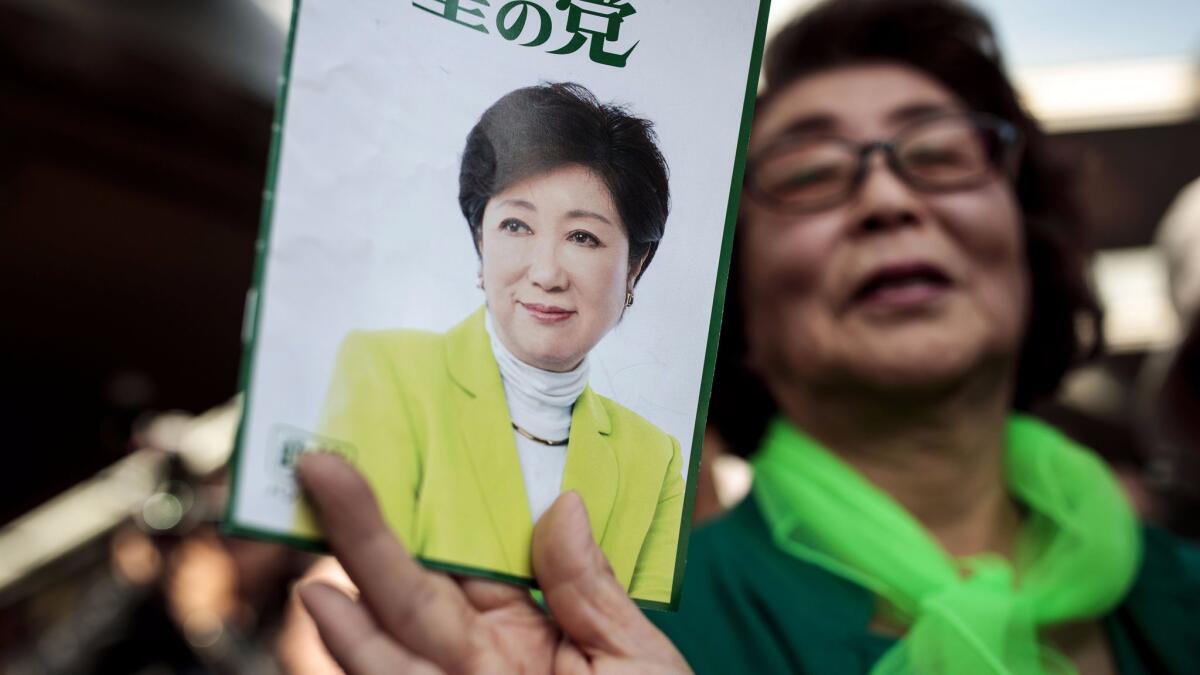 A woman shows an electoral leaflet of Tokyo Gov. Yuriko Koike during an election event in Saitama on Oct. 18.