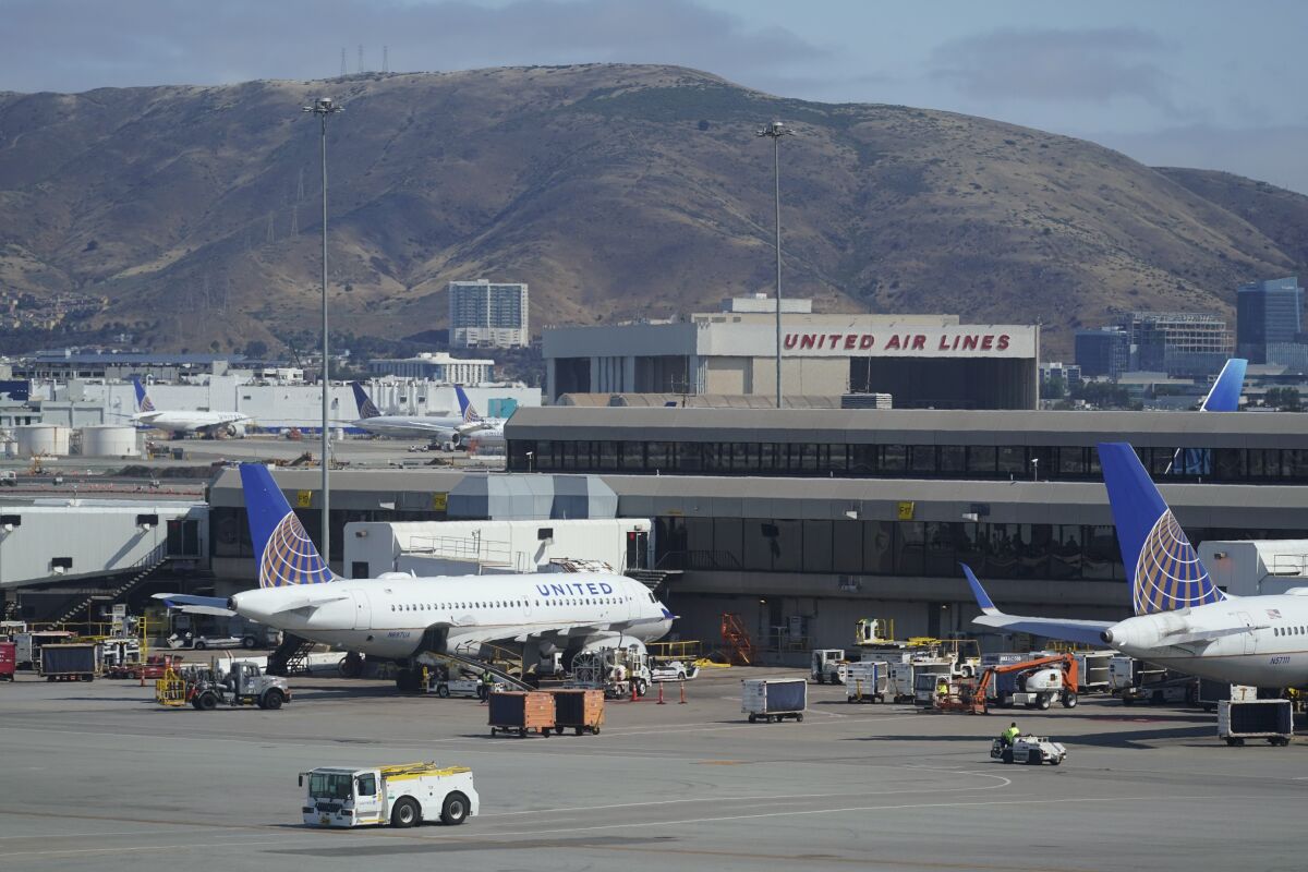 FILE - United Airlines planes are seen parked at San Francisco International Airport with a maintenance hangar in the background on Wednesday, July 14, 2021, in San Francisco. A federal judge has extended on Tuesday, Oct. 12, a ban on United Airlines putting employees on unpaid leave for seeking a medical or religious exemption from the airline's requirement to get vaccinated against COVID-19. (AP Photo/Eric Risberg, File)