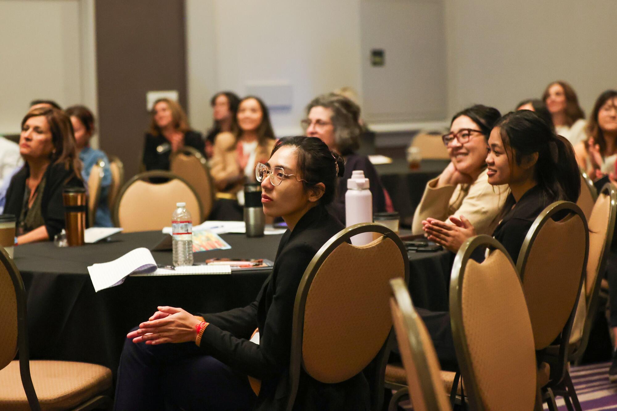 A group of people seated at tables in a hotel conference room