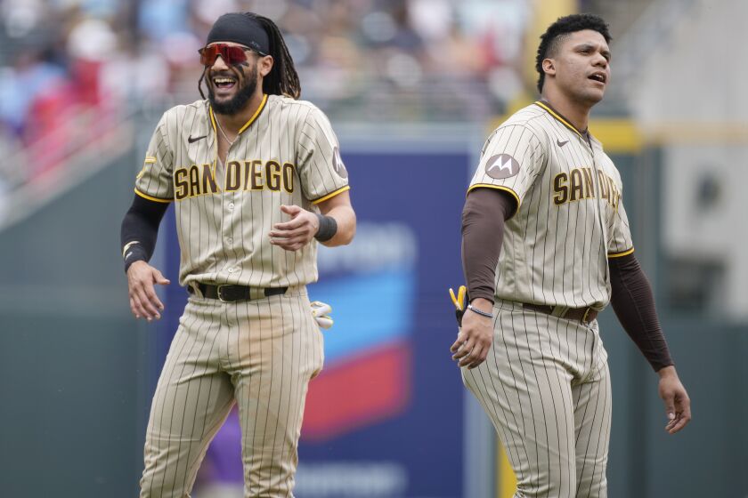 San Diego Padres right fielder Fernando Tatis Jr., left, jokes with left fielder Juan Soto as they wait for their fielding apparel to return to their positions after the top of the sixth inning of a baseball game against the Colorado Rockies, Saturday, June 10, 2023, in Denver. (AP Photo/David Zalubowski)