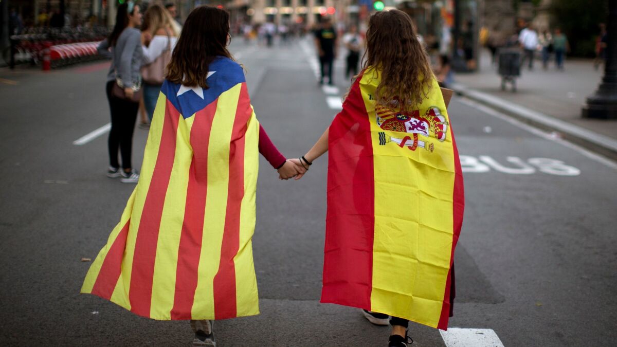 Mariona Esteve, 14, left, wears a Catalan independence flag, and Irene Guszman, 15, wears a Spanish flag at a demonstration in Barcelona, Spain.