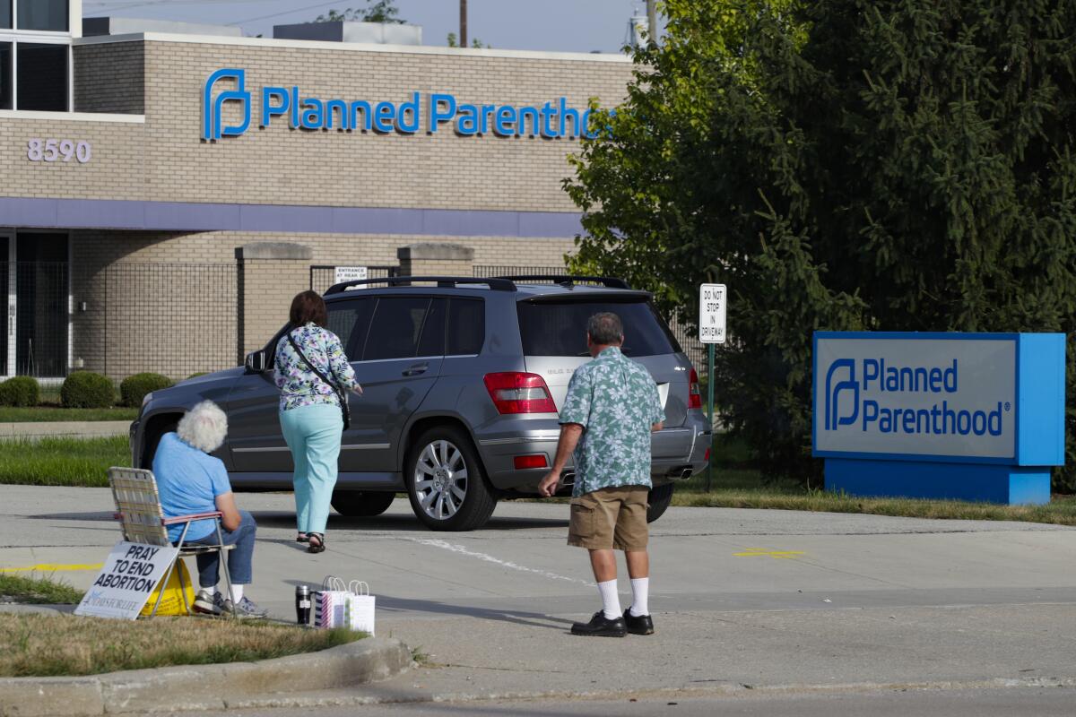 FILE - In this Aug. 16, 2019 file photo, abortion protesters attempt to handout literature as they stand in the driveway of a Planned Parenthood clinic in Indianapolis. A federal judge has blocked a new Indiana law that would require doctors to tell women undergoing drug-induced abortions about a disputed treatment for potentially stopping the abortion process. The ruling Wednesday, June 30, 2021, came just before the so-called abortion reversal law adopted by Indiana’s Republican-dominated Legislature was to take effect Thursday. (AP Photo/Michael Conroy)