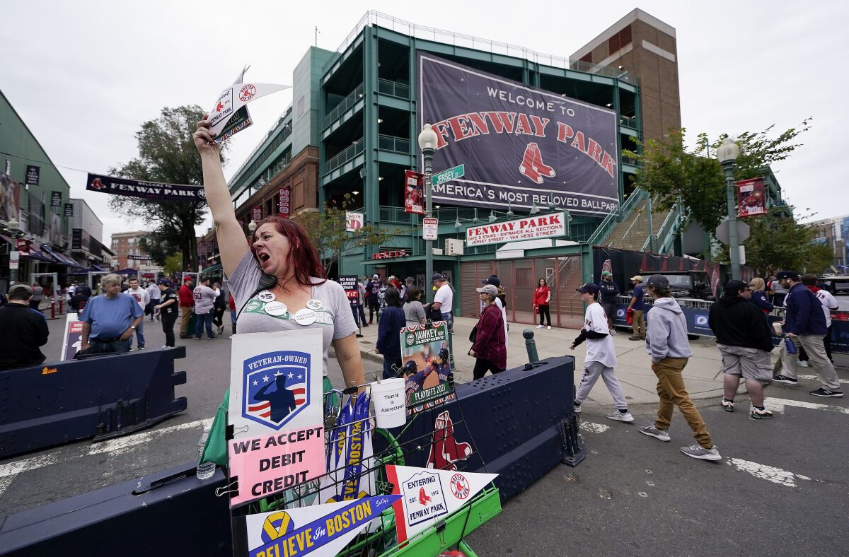 Vendor Patricia Almquist, of North Oxford, Mass., sells souvenirs outside Fenway Park before game 3 of a baseball American League Division Series between the Boston Red Sox and the Tampa Bay Rays, Sunday, Oct. 10, 2021, in Boston. (AP Photo/Charles Krupa)