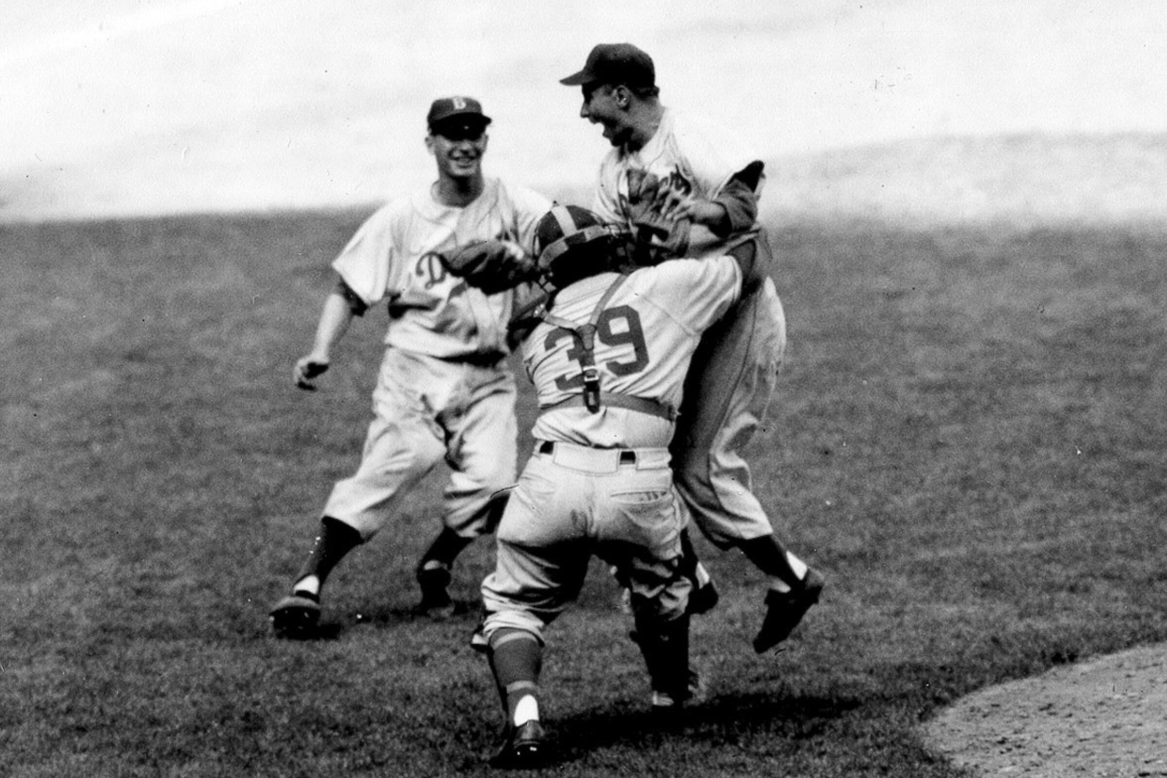 Brooklyn Dodgers pitcher Johnny Podres is lifted by catcher Roy Campanella.