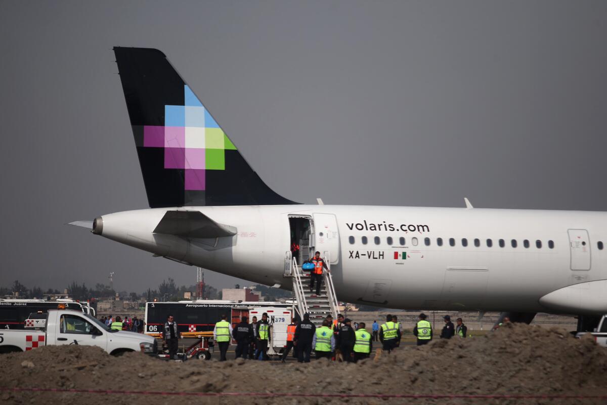 La policía y personal de tierra rodean el avión de la aerolínea Volaris después que las autoridades retrasaran el vuelo y llevaran a los pasajeros a un área de seguridad luego que un pasajero anunciara que había una bomba en el aeropuerto internacional de ciudad de México, el martes 8 de diciembre de 2015. Se informó que tras una búsqueda no se encontró ningún artefacto explosivo. (AP Photo)