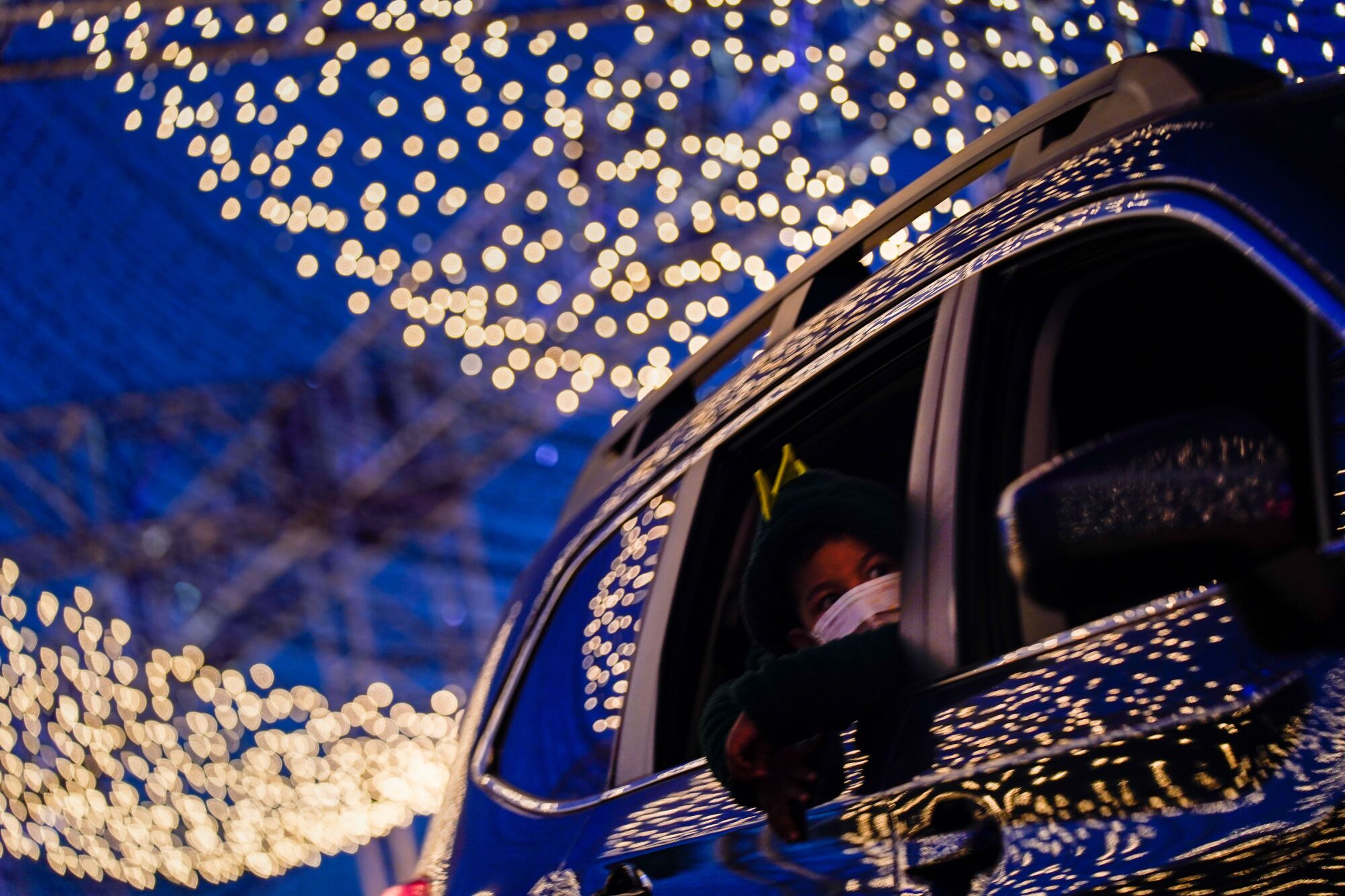 A child looks out of a car window as it makes its  way through the Dodger's Holiday Festival 2020 