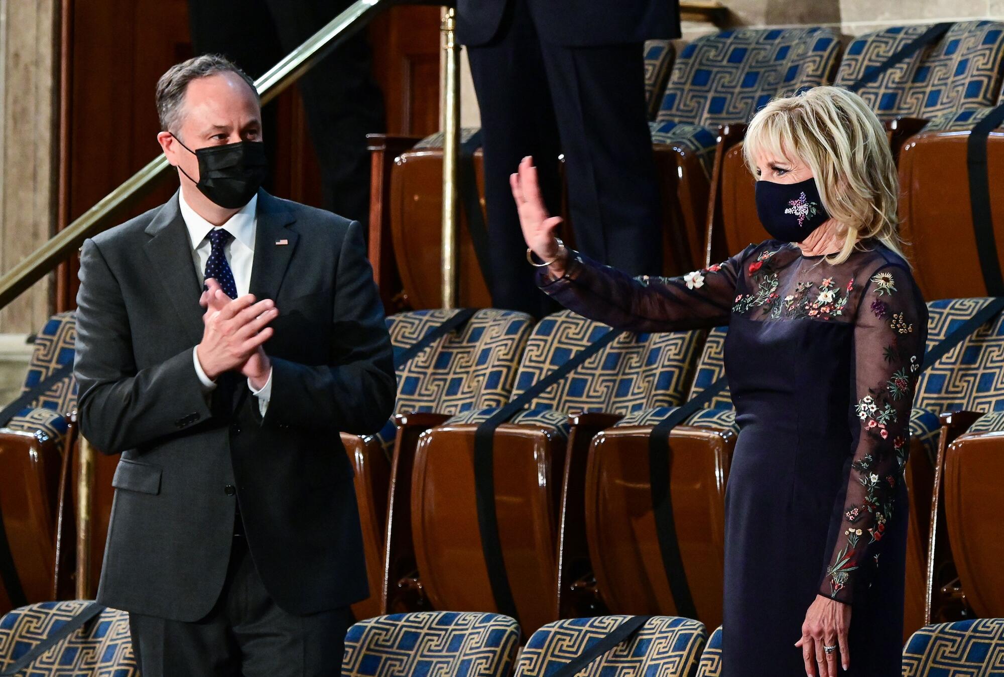 A woman raises her right hand as a man nearby applauds.