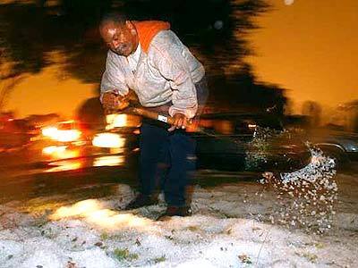 Gerald Pickens shovels hail from his front yard on Central Ave in South L.A. A rare storm battered parts of the Southland with rain and hail on Wednesday evening.